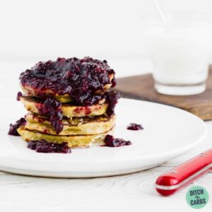 A stack of Paleo pancakes on a plate with fresh berry sauce