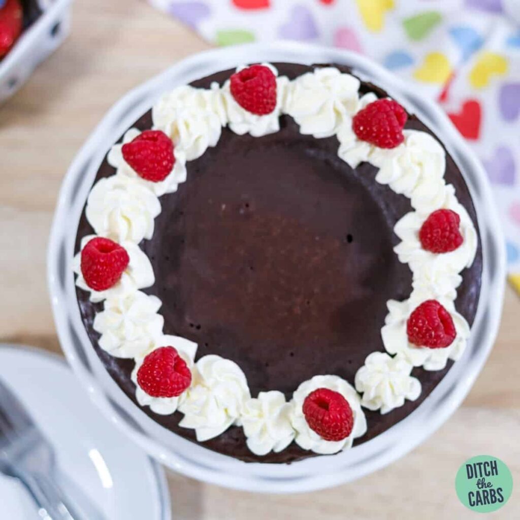 keto chocolate cake decorated with whipped cream and berries