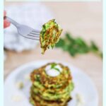 keto zucchini fritters stacked on a white plate and a fork