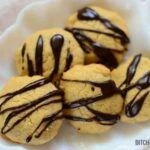 Peanut butter cookies drizzled with dark sugar-free chocolate on a white plate