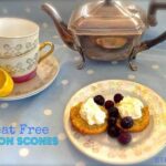 Low-carb lemon scones served on an antique plate with whipped cream and fresh berries in front of an antique silver teapot