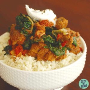 low-carb lamb curry with spinach served on cauliflower rice in a white bowl