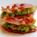 Two slices of bacon with avocado in between for a sandwich on a plate