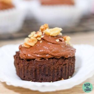 a chocolate cupcake covered in chocolate frosting wth a walnut on top