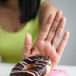 woman pushing away a plate of donuts