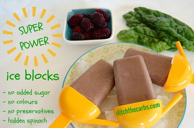 Chocolate popsicles on a plate with fresh berries and spinach in the background