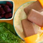 Chocolate popsicles with spinach leaves and fresh berries on a plate
