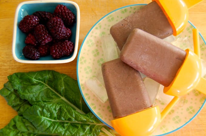 Chocolate popsicles with spinach leaves and fresh berries on a plate