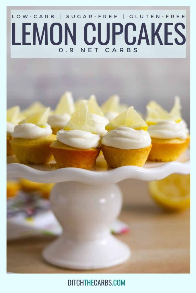 a white cake stand with a dozen keto lemon cupacke with creamy lemon frosting and a slice of lemon