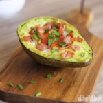 A slice of avocado sitting on top of a wooden cutting board 