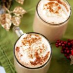 Creamy low carb eggnog served in glass mugs whipped cream and nutmeg with Christmas decorations