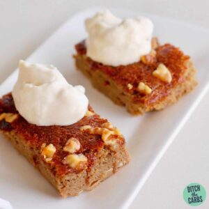 A piece of walnut and coffee cake on a plate with whipped cream