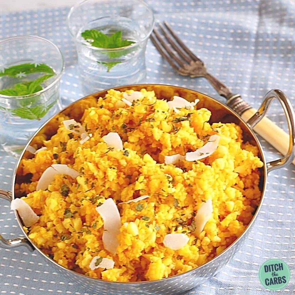 A bowl of curried cauliflower rice with water and antique cutlery