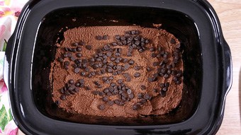 A close up of a chocolate lava cake sitting in the slow cooker sprinkled with sugar-free chocolate chips