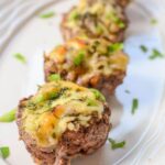 Mini meatloaf cupcakes with melted cheese and garnished with herbs