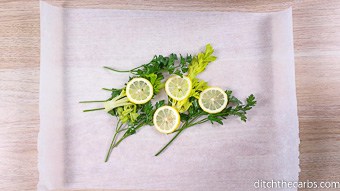 Fish herbs and lemon slices sitting on parchment paper