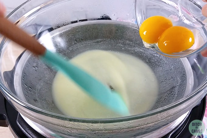 A bowl of melted butter with two eggs being stirred in