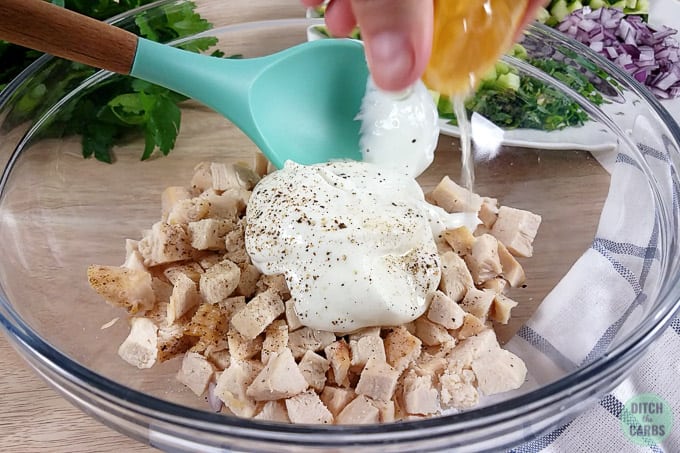 A bowl of chopped chicken with mayonnaise poured over