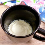 Butter and cream cheese melted together in a black mug.