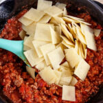 Keto pasta sits on top of the meat sauce ready to be mixed into the skillet.