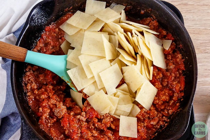 Keto pasta sits on top of the meat sauce ready to be mixed into the skillet.