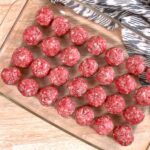 Uncooked keto meatballs in a glass baking pan ready to be cooked.
