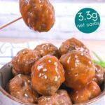 Sweet and sour keto meatballs being served in a blue stone bowl. One meatball is being lifted with a toothpick.