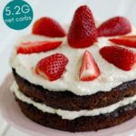 Low-Carb Chocolate Zucchini Cake served with whipped cream and berries on a white plate with strawberries