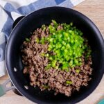 Browned ground beef and chopped green bell pepper in a skillet.