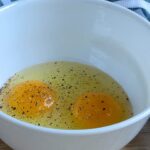 2 eggs and pepper in a white bowl