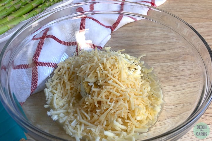 A bowl of shredded cheese in a glass mixing bowl