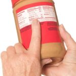 food label showing carbohydrates in peanut butter held by handa