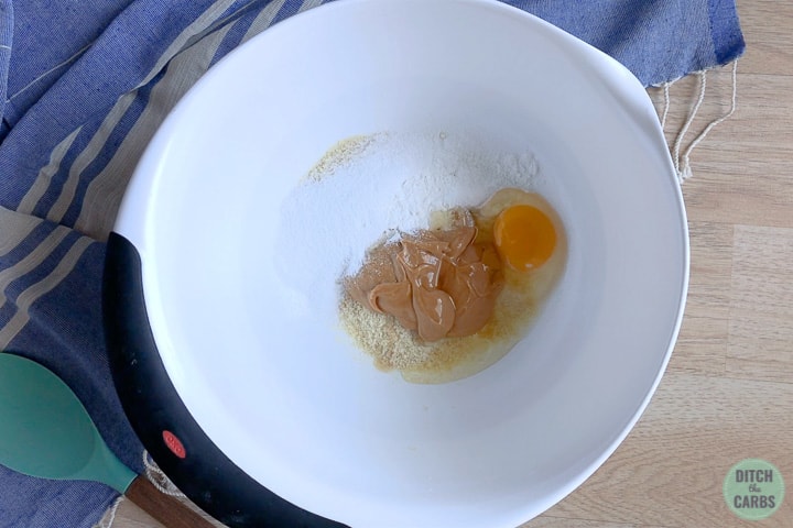 A mixing bowl with sweetener peanut butter and an egg