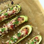 cooked zucchini taco boats on baking parchment and served with salsa and cheese
