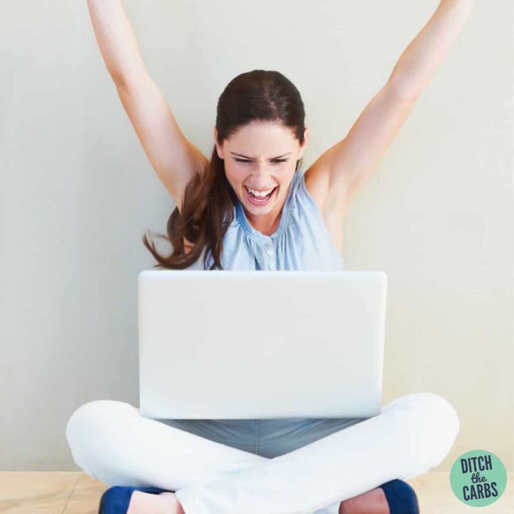 woman with hands in air holding a laptop