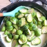 Creamy cheese sauce make in a skillet. The brussels sprouts have been cut in half and added to the skillet.