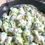 Brussels sprouts tossed in the cheese sauce in the skillet so that they are completed coated.