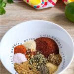 All the ingredients for keto taco seasoning is measure and placed in a white bowl.