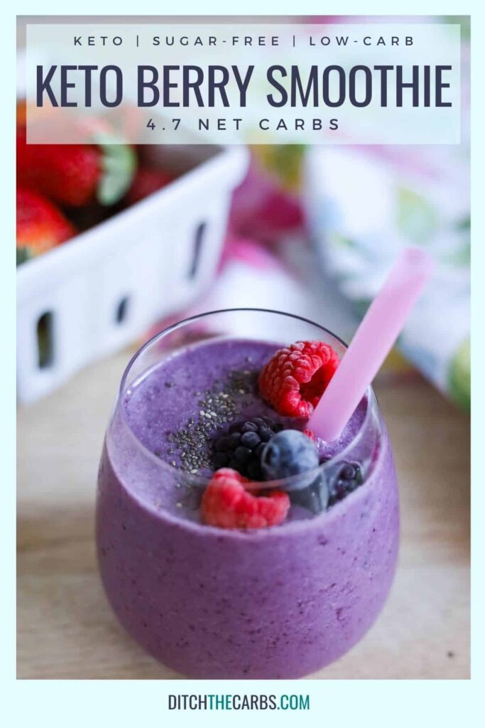 Keto Berry Smoothie poured in a clear glass cup with frozen berries and chia seeds sprinkled on top. A pink straw is sticking out of the top of the smoothie.