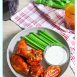 Air Fryer Chicken Wings Tossed in Keto BBQ sauce on a plate with a side of keto ranch and celery.