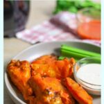Air Fryer Chicken Wings Tossed in Keto buffalo sauce on a plate with a side of keto ranch and celery.