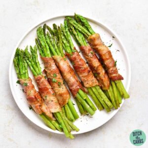 bacon wrapped asparagus baked and on a white plate