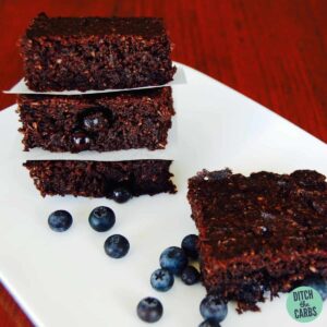 Sugar free chocolate berry brownie stacked on a plate and served with fresh blueberries