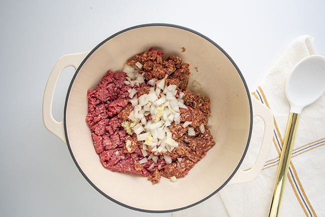 Browning the ground beef, sausage, garlic, and onion in a pot