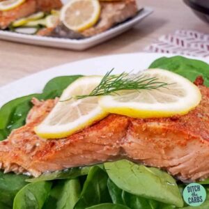 Poached salmon on a bed of lettuce garnished with a slice of lemon in front of the instant pot
