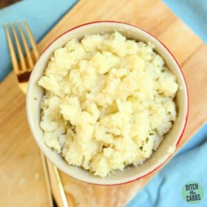 Mashed cauliflower on a wooden board and gold fork