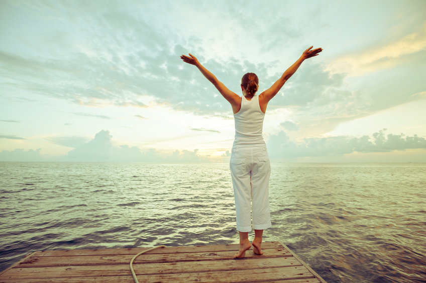 A woman lifting her hands up to the sky, happy that she is experiencing low-carb diet benefits 