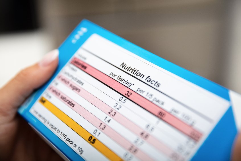 A woman reading nutrition facts on the back of a box.