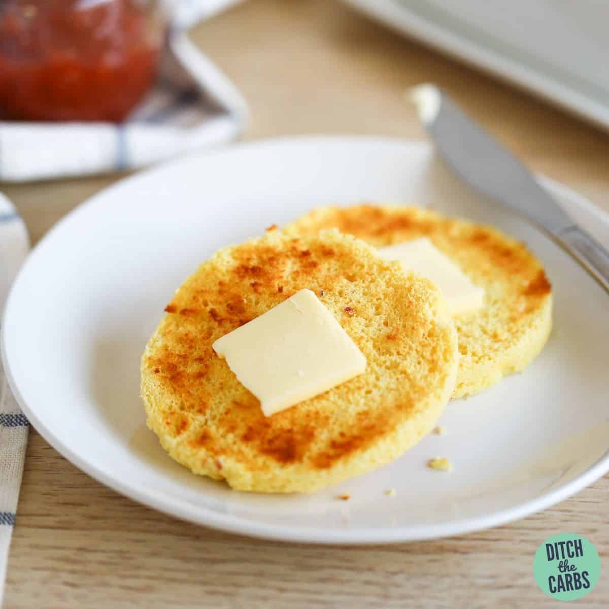 Low-carb English muffin cut in half and toasted with a pat of butter on each half.